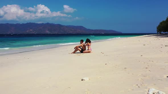 Teenage lovers happy together on paradise shore beach trip by blue green lagoon and white sand backg