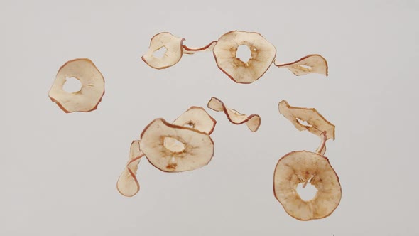 Crispy Apple Chips Jump and Fall on Isolated White Background