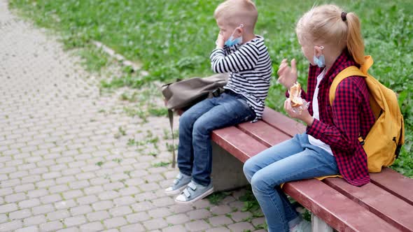 Back to School Girl and Boy Children Sit Talking on Bench Near the School Keeping Social Distance