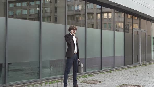 Businessman talking to employees on the phone near the office