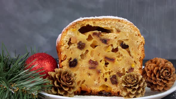 Powdered sugar poured onto Christmas Stollen fruit cake on dark background Festive pastry baking 4K