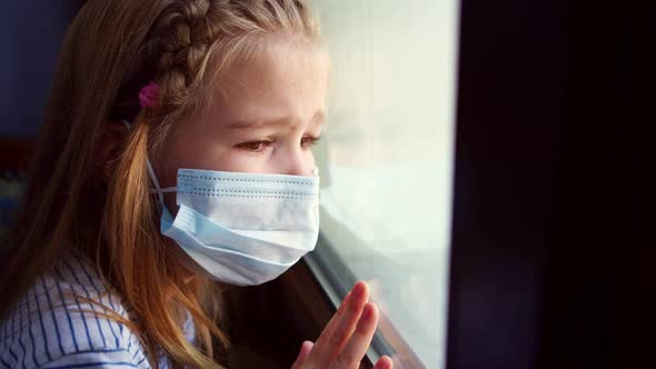 Little Girl in Protective Mask Look Out of Window Outside