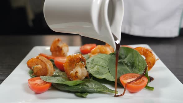 Mediterranean Cuisine. Chef Pours Sauce Over Vegetarian Seafood Salad with Shrimps. Finishing Salad