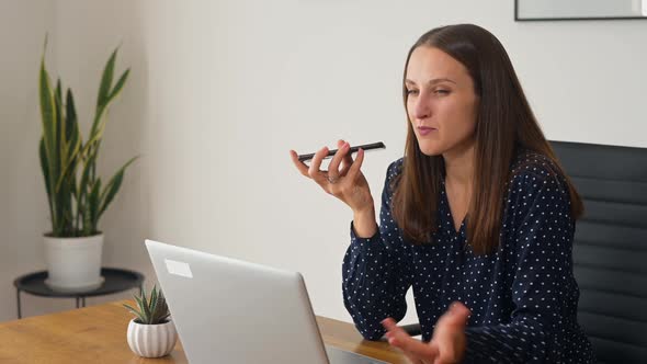 Smiling Young Businesswoman Using Voice Recognition Function on a Smartphone