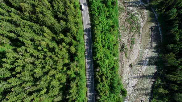 Aerial top view of mountain twisted road and Van or Bus driving to the mountains. Transportation.