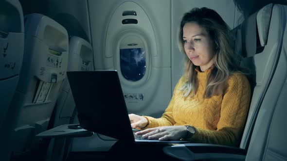 Beautiful Woman Is Operating a Laptop During Night Flight