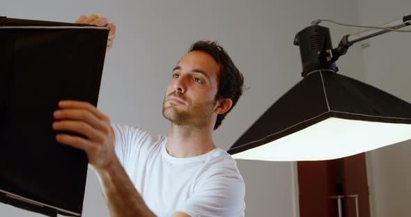 Male photographer adjusting strobe light