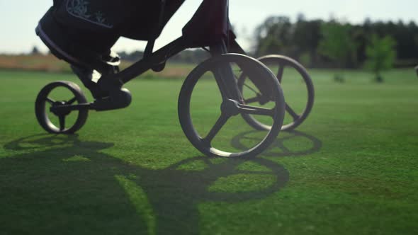 Golf Player Using Clubs Trolley on Course