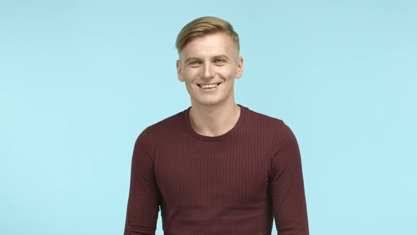 Attractive Caucasian Male Model with Blond Hair Looking at Camera Start to Laugh and Smile with