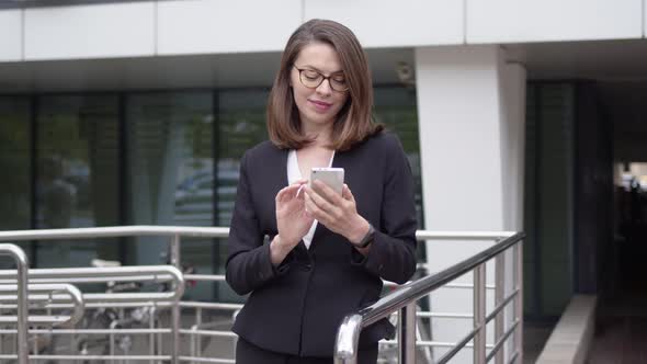 Business Woman Standing in Front of Office Building Using Phone