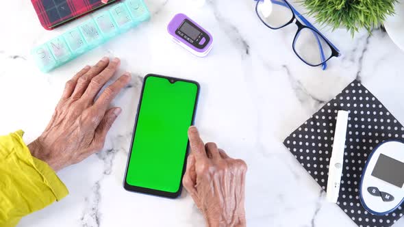 Senior Women Using Smart Phone and Glucometer on Table