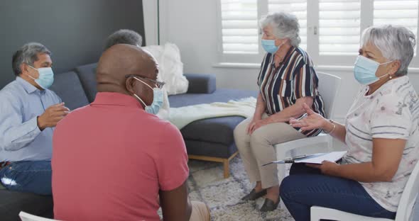 Group of diverse senior friends in face masks having support meeting