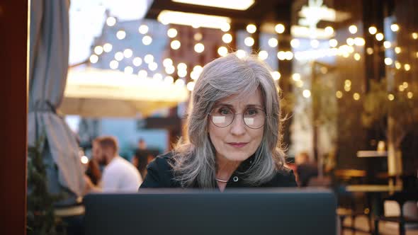 Lovely Middleaged Woman is Sitting in a Cafe with a Laptop and She is Happy to See the Good News