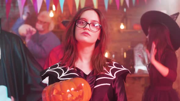 Teen Girl in Evil Witch Costume with a Jack-o-lantern in Her Hands