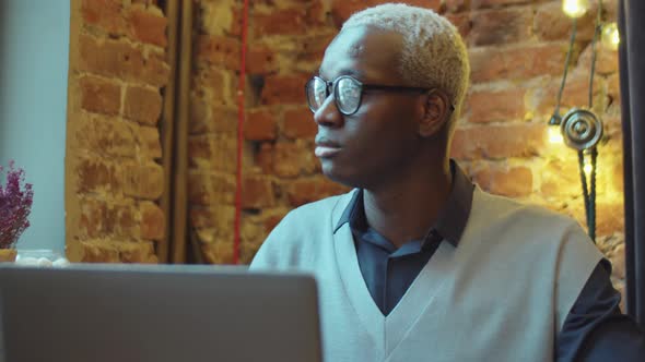 Young Black Man Working on Laptop in Cafe