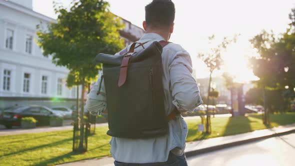 Attractive Young Handsome Man Tourist with Backpack Walking in City Center and Looking Around Slow