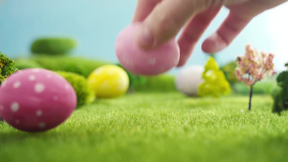 Hand Laying Easter Egg on Grass