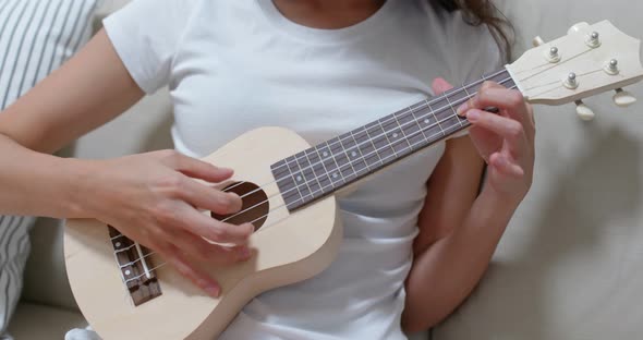 Woman play ukulele at home