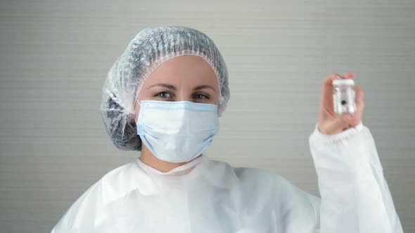 A Female Doctor in a Medical Mask Holds Money in Her Hands