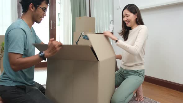 Happy asian   couple holding boxes entering new modern house