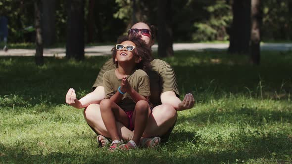 White Woman and Her Black Daughter Sitting on the Grass in the Park  Meditating and Having Fun