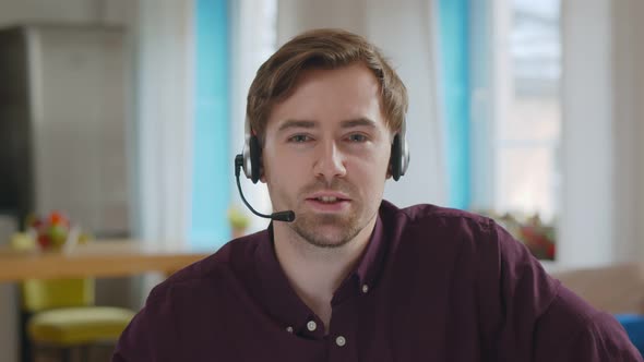 Portrait of Young Businessman in Headset Having Online Business Meeting Making Report Sitting at