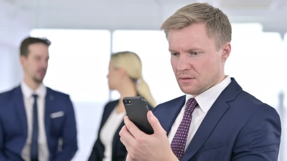 Portrait of Disappointed Businessman Reacting To Failure on Smartphone