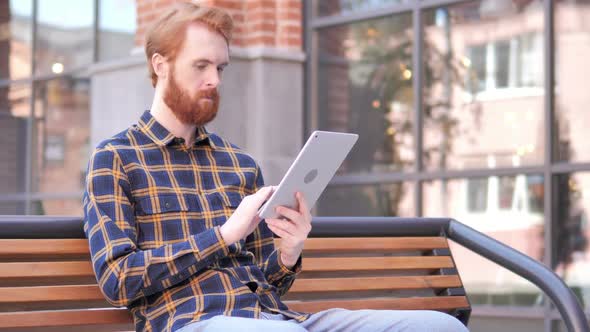 Redhead Beard Young Man Using Tablet While Sitting on Bench