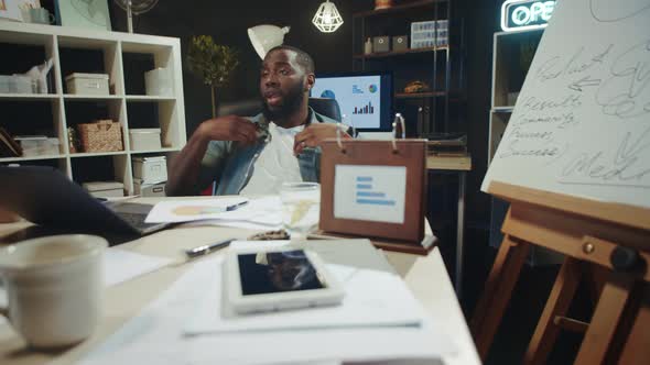 Portrait of African American Manager Having Fun Near Laptop in Hipster Office.