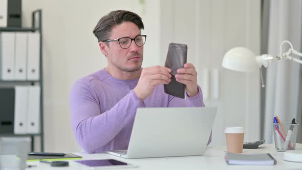 Middle Aged Man with Laptop Checking Empty Wallet