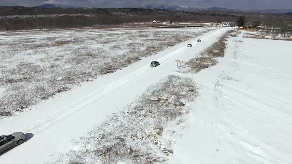 View From a Drone on a Winter Road in a Field Along Which Cars Drive