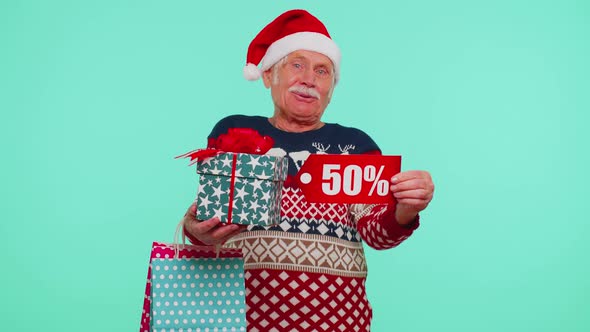 Elderly Man in Christmas Sweater Showing Gift Box and 50 Percent Discount Inscriptions Banner Text