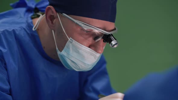 Portrait of Concentrated Surgeon with Scalpel Making Dissection on Patient in Surgery Room in