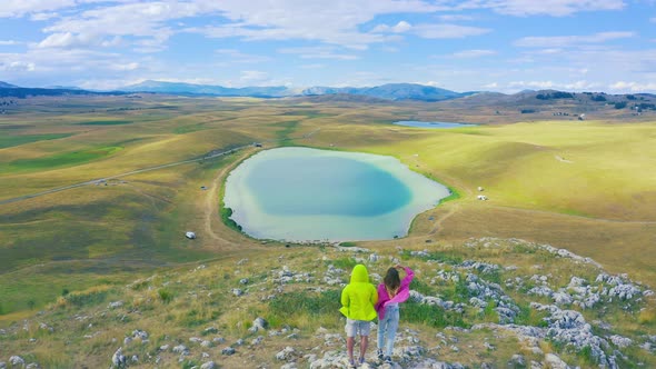 Couple Tourists Men and Women Stand on the Shore of a Picturesque Azure Lake a Summer Day