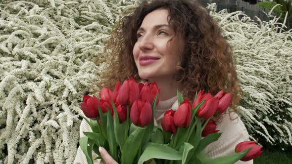 Portrait of a Happy Woman with a Bouquet of Red Tulips