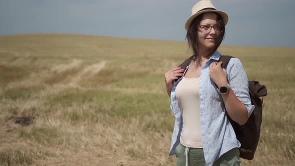 Woman Traveler with a Backpack Walks on a Hill