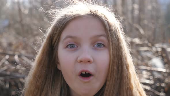 Happy Little Blonde Girl Looking Into Camera with Wow Expression Outdoor. Portrait of Beautiful