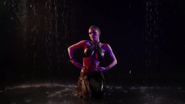 Enigmatic Sexy Belly Dancer is Standing on Knees Under Rain at Night and Dancing Moving Hands