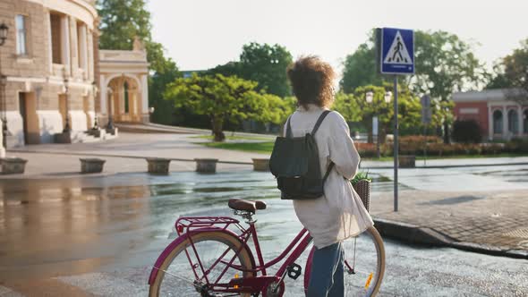 Africanamerican Lady Walking with Bicycle By Deserted Street Along Beautiful Building