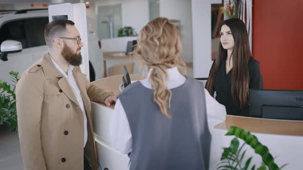 Friendly Woman Administrator Meets Buyers in the Showroom of New Cars