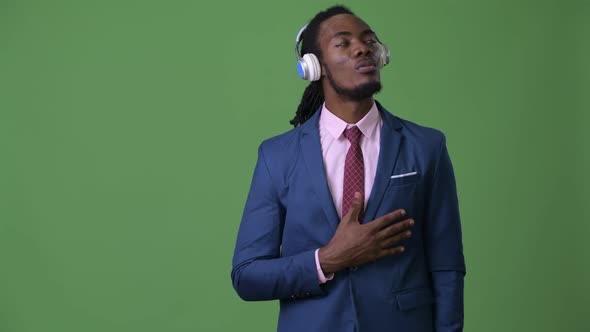 Young Handsome African Businessman with Dreadlocks Against Green Background