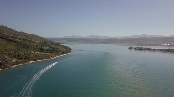 High aerial in Knysna Lagoon as speed boat cuts white wake in water