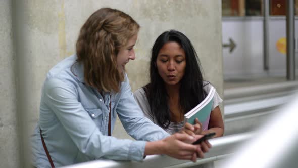 Women looking up from smartphone and laughing, shot from personal perspective