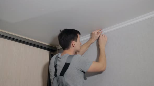 Man Applying Ceiling Molding in Room