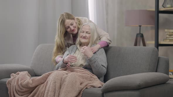 Wide Shot Portrait of Smiling Happy Old Woman Sitting on Couch As Senior Lady Hugging Mother Looking