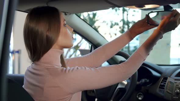 Girl Adjusts Rear-view Mirror Inside the Car