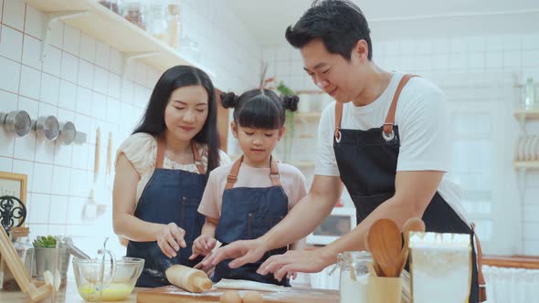 Asian happy family, Parents teach young little daughter doing homemade bake bakery in kitchen.