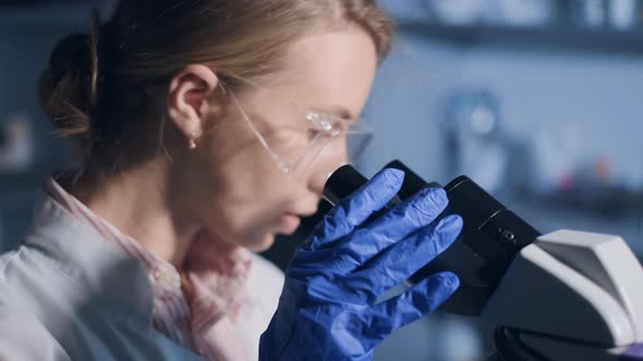 A Woman Scientist is Looking Into Microscope Biochemical Research