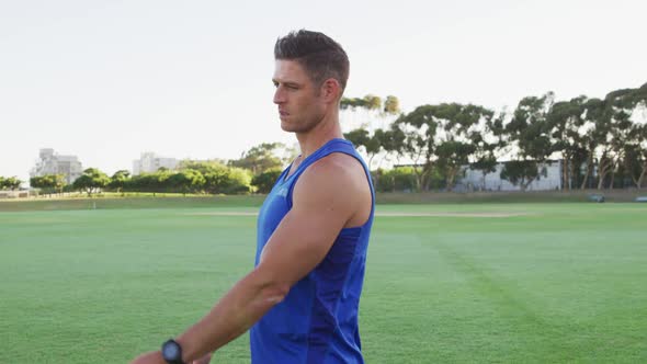 Smiling fit caucasian man exercising outdoors stretching from the waist