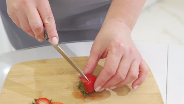 Strawberries are Cut Into Pieces on a Wooden Cutting Board to Decorate Desserts
